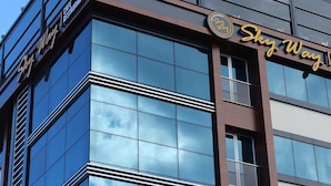 Um edifício moderno com fachada de vidro refletante, exibindo a sinalização 'Sky Way' e 'Cafe Restaurant'.