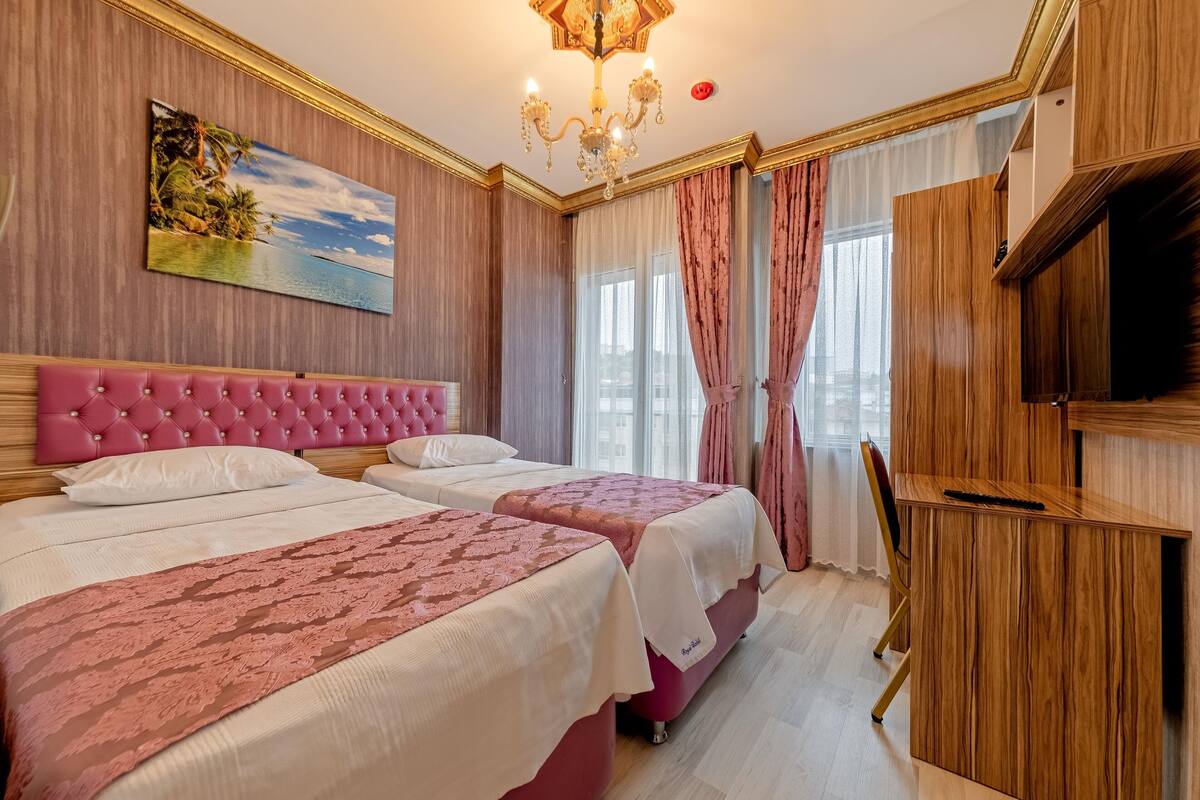 Una habitación de hotel con dos camas, un televisor, un armario de madera y un cuadro de una playa tropical.
