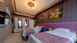 Quarto de hotel com duas camas, uma janela grande, um candelabro e um quadro na parede.