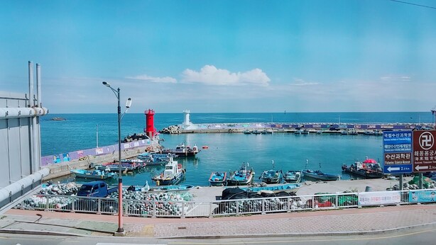 Un puerto con barcos amarrados, un faro y un muelle que se adentra en el agua.