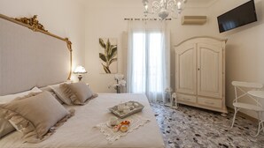 A bedroom with a bed, a chandelier, a wardrobe, a TV, and a small table. - PalazzinApulia (Fasano)