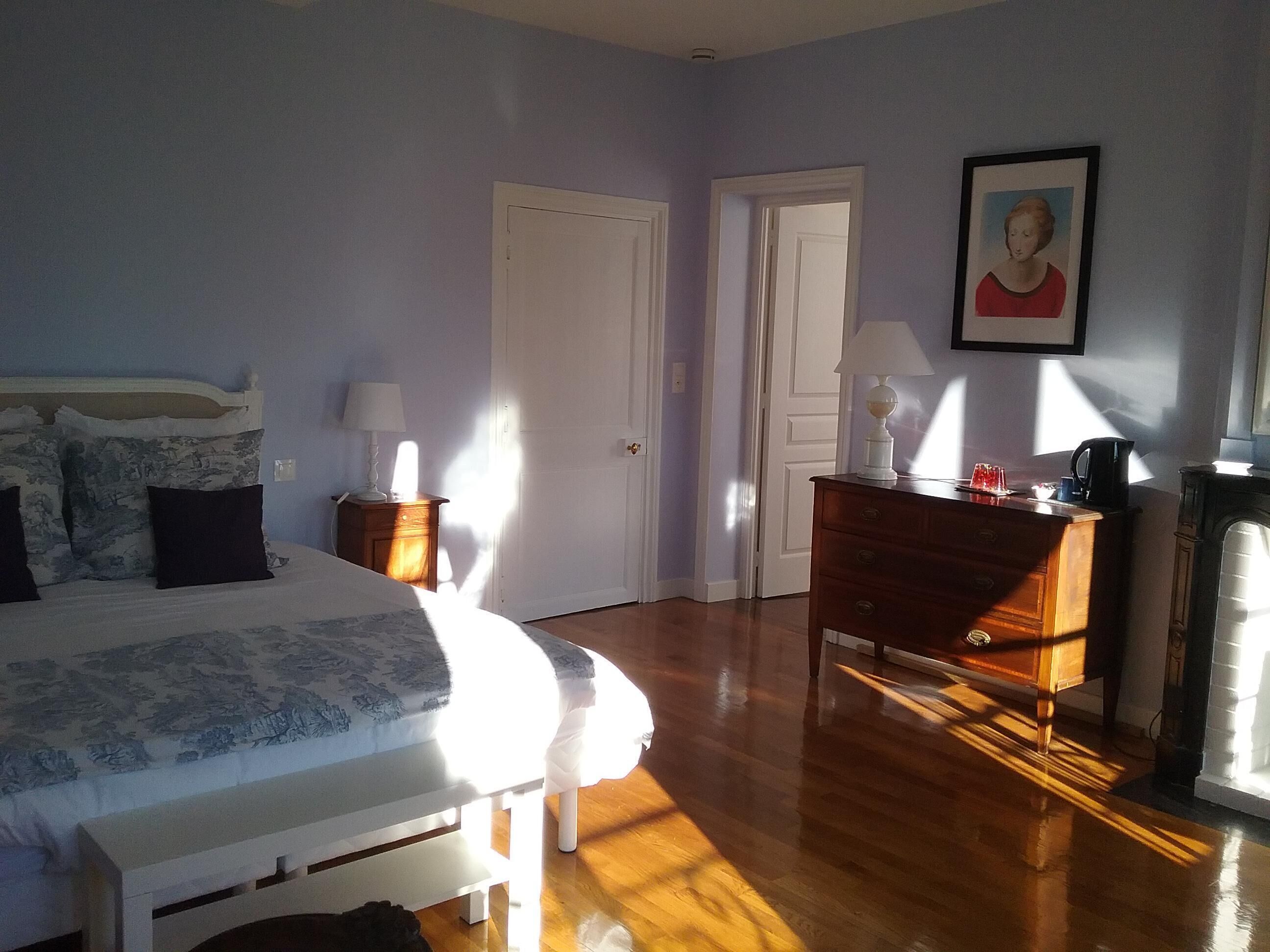 Ein Schlafzimmer mit einem Bett, Nachttischen, einer Kommode und einem gerahmten Bild an der Wand.