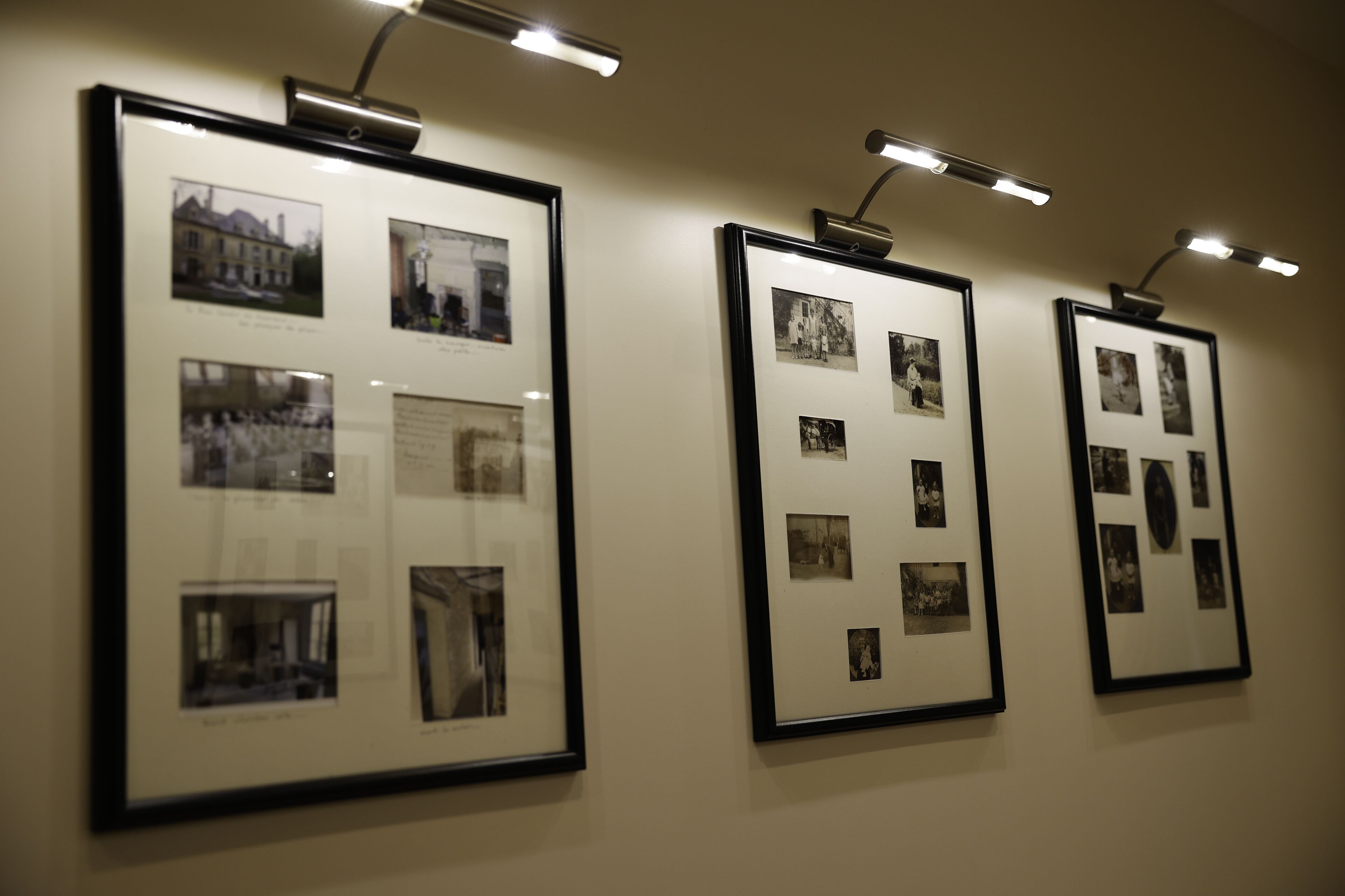Ingelijste foto’s aan een muur, elk met een onderschrift eronder.