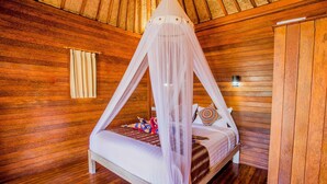 A wooden-paneled room with a bed under a canopy, a nightstand, and a wall-mounted light.