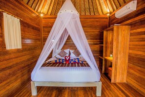 A wooden room with a bed under a canopy, a wooden wardrobe, and an air conditioning unit. - Sea Bridge Villa Ceningan (Ceningan Island)
