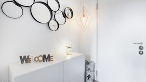 A modern reception area with a white console, a welcome sign, decorative mirrors, and a geometric pendant light. - Italianway   - Passeroni 2 (Milan)