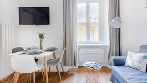 A modern living room with a dining area, a flat-screen TV, a sofa, and a window with curtains. - Italianway   - Passeroni 2 (Milan)