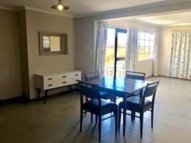 Un comedor con una mesa, sillas, un armario blanco y una ventana con cortinas.