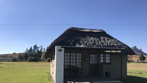 A small, single-story building with a thatched roof, a porch, and a small front yard. - Windmill Farm (Jagersrust)