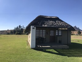 Un pequeño edificio de un piso con techo de paja, un porche y un pequeño jardín delantero.