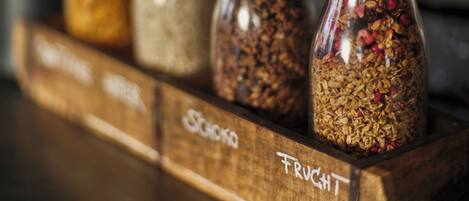 A wooden rack with labeled glass jars containing different types of granola.