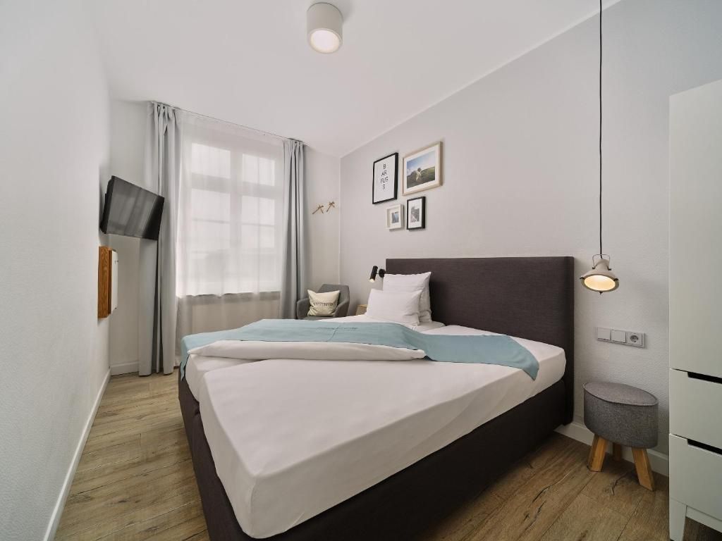 A modern bedroom with a large bed, a flat-screen TV mounted on the wall, and a bedside table with a lamp.