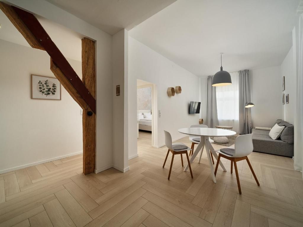 A modern living space with a dining area, a sofa, and a staircase.