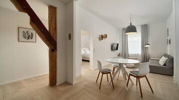 A modern living space with a dining area, a sofa, and a staircase.