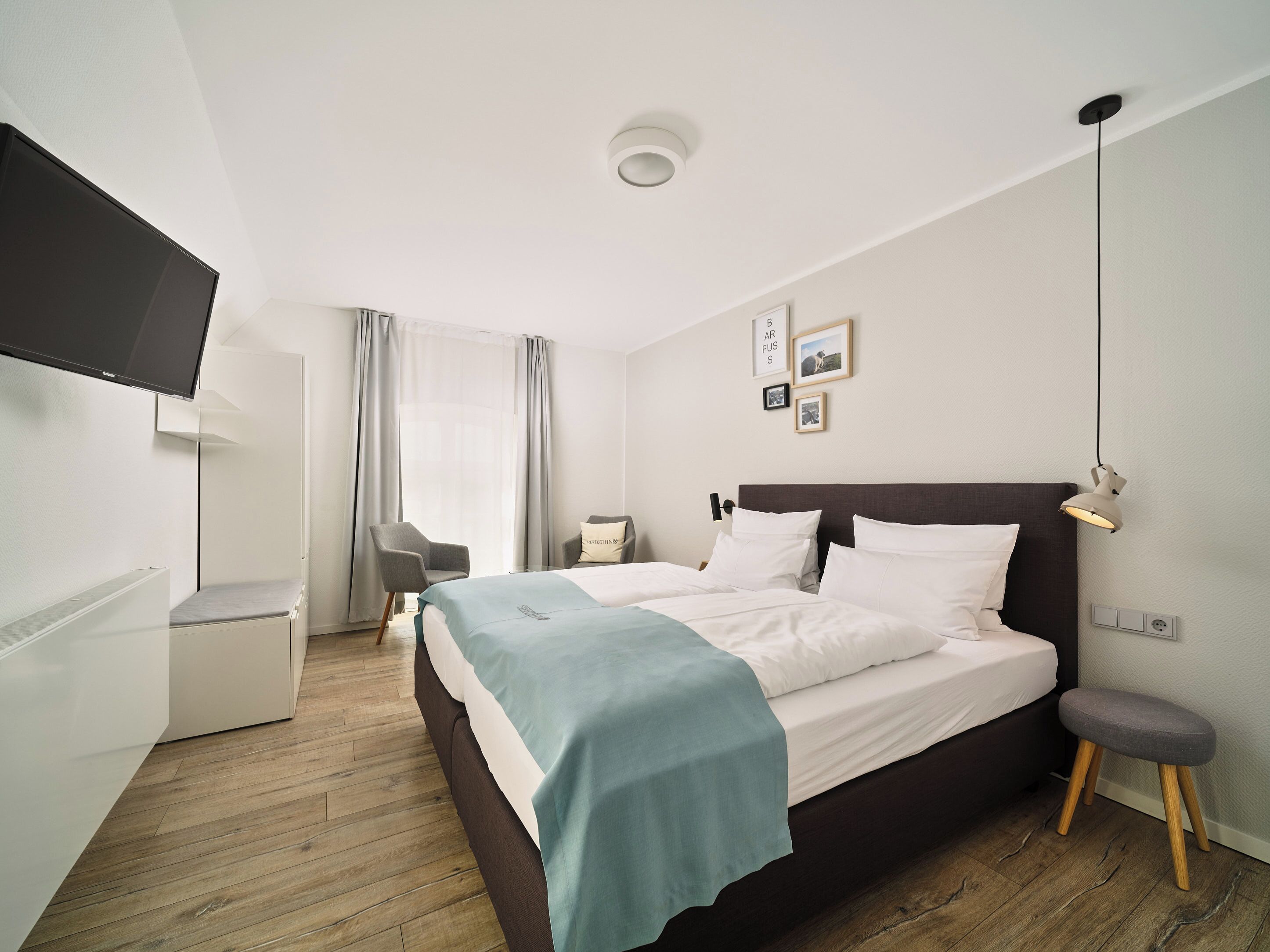 Ein modernes Hotelzimmer mit Bett, Schreibtisch, Stuhl und Fernseher.