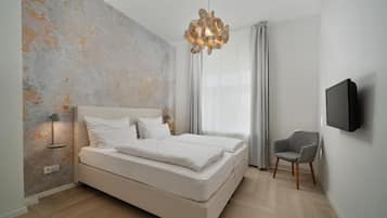 Un dormitorio moderno con una cama, una silla, un televisor y una original obra de arte en la pared.