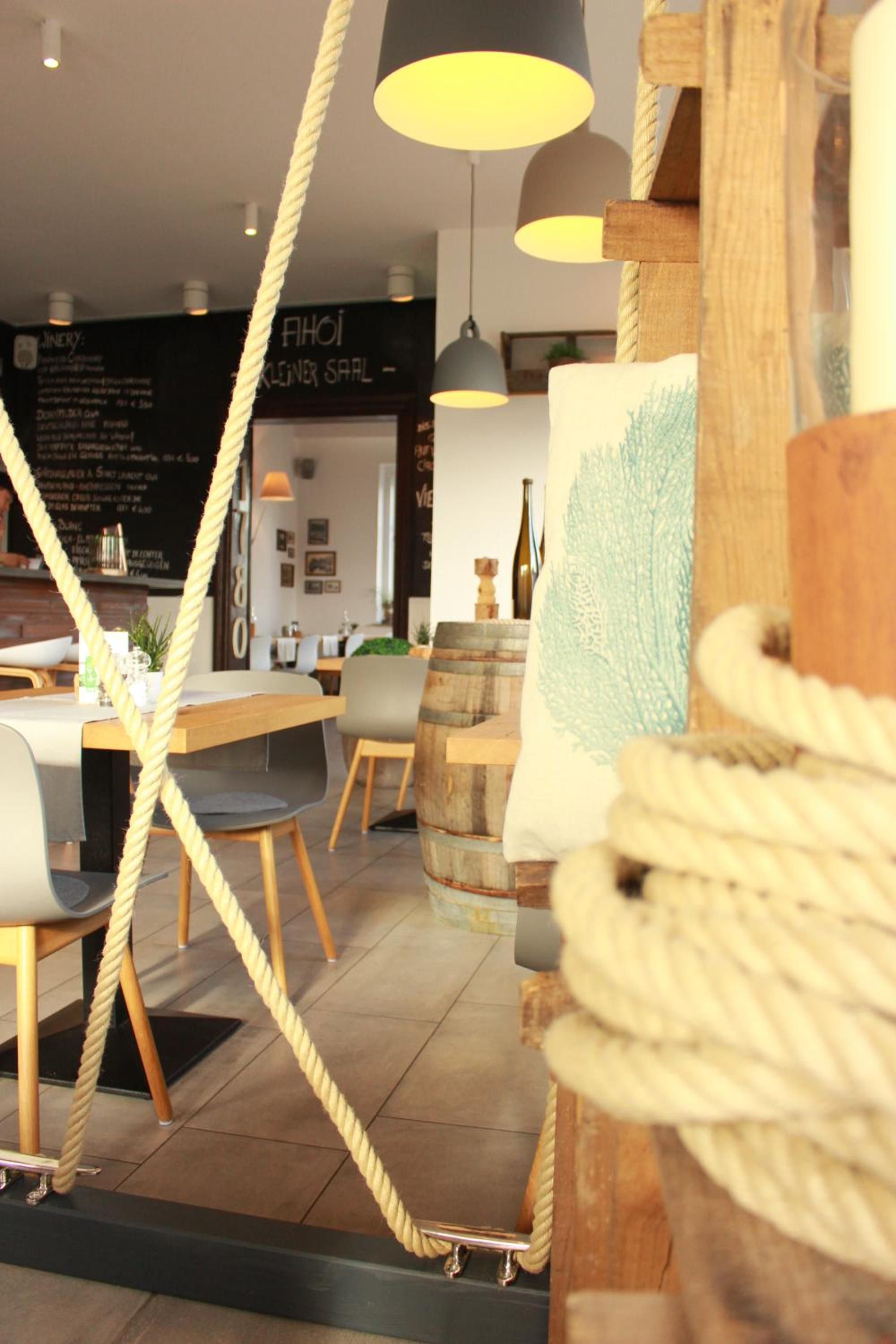 A modern interior with a dining area featuring a wooden table and chairs, a blackboard menu, and a rope installation.
