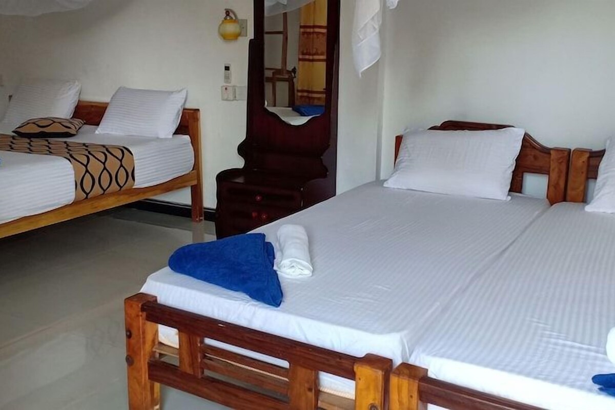 Ein Hotelzimmer mit zwei Einzelbetten, einem Holzkopfteil und einem Spiegel.