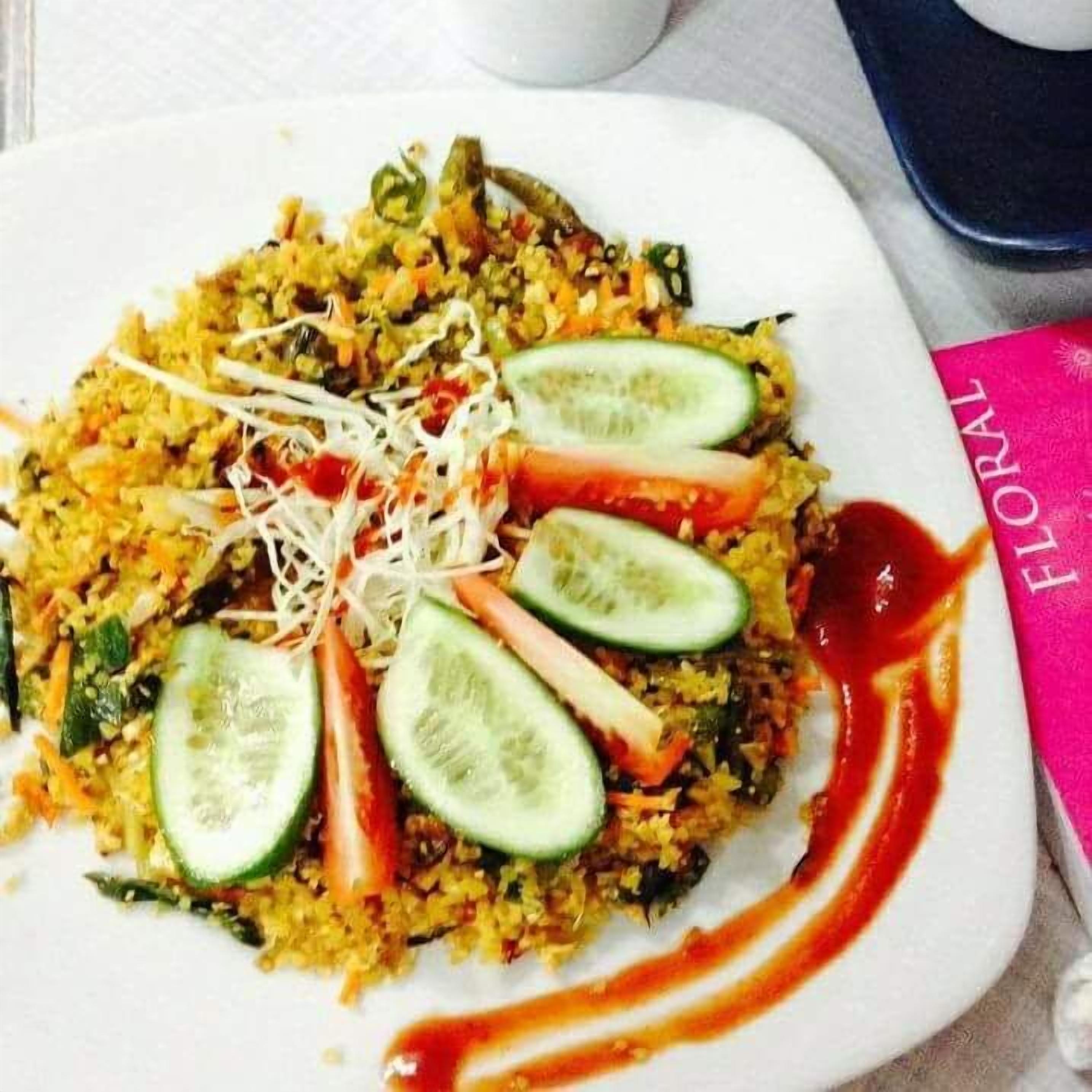 A plate of food with rice, vegetables, and a red sauce.