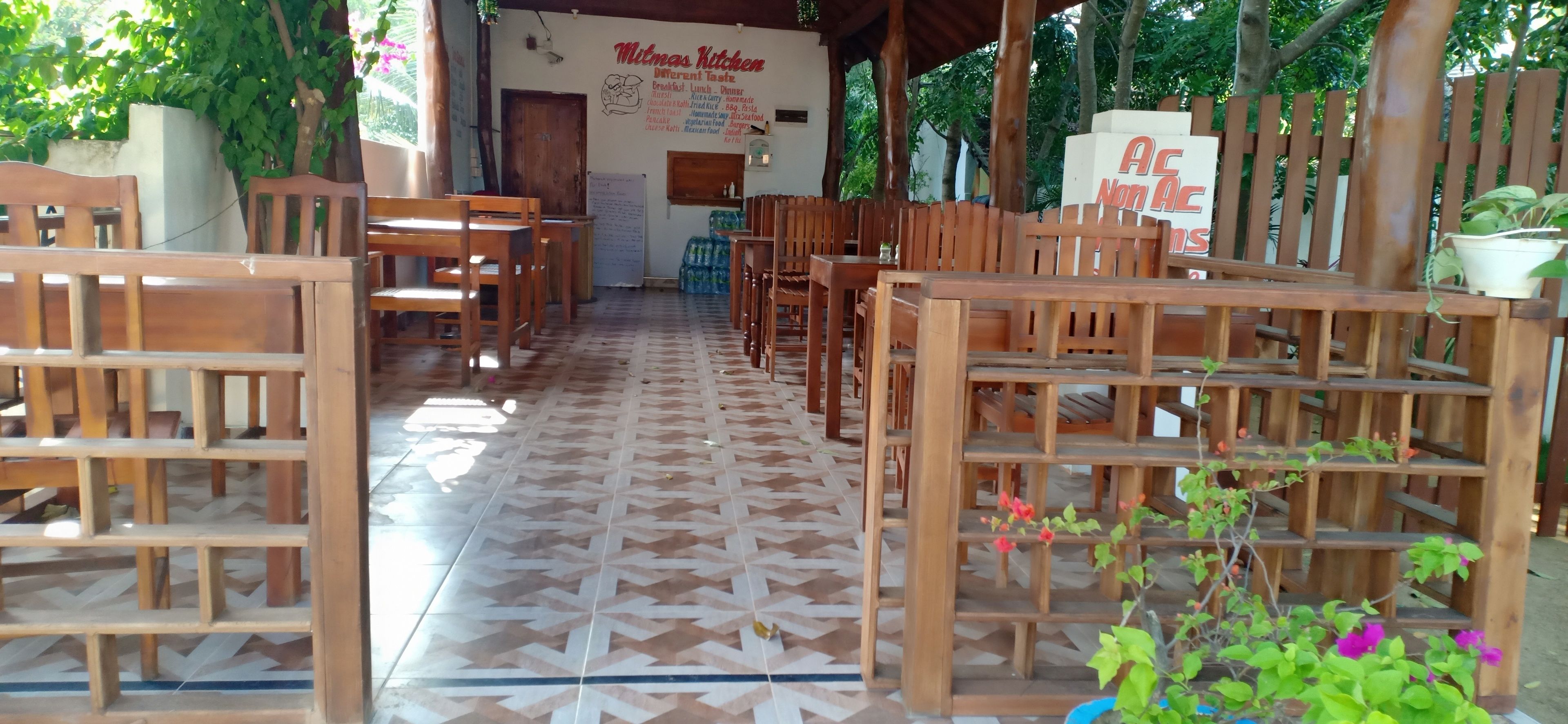 A restaurant with wooden tables and chairs, a tiled floor, and a menu board.