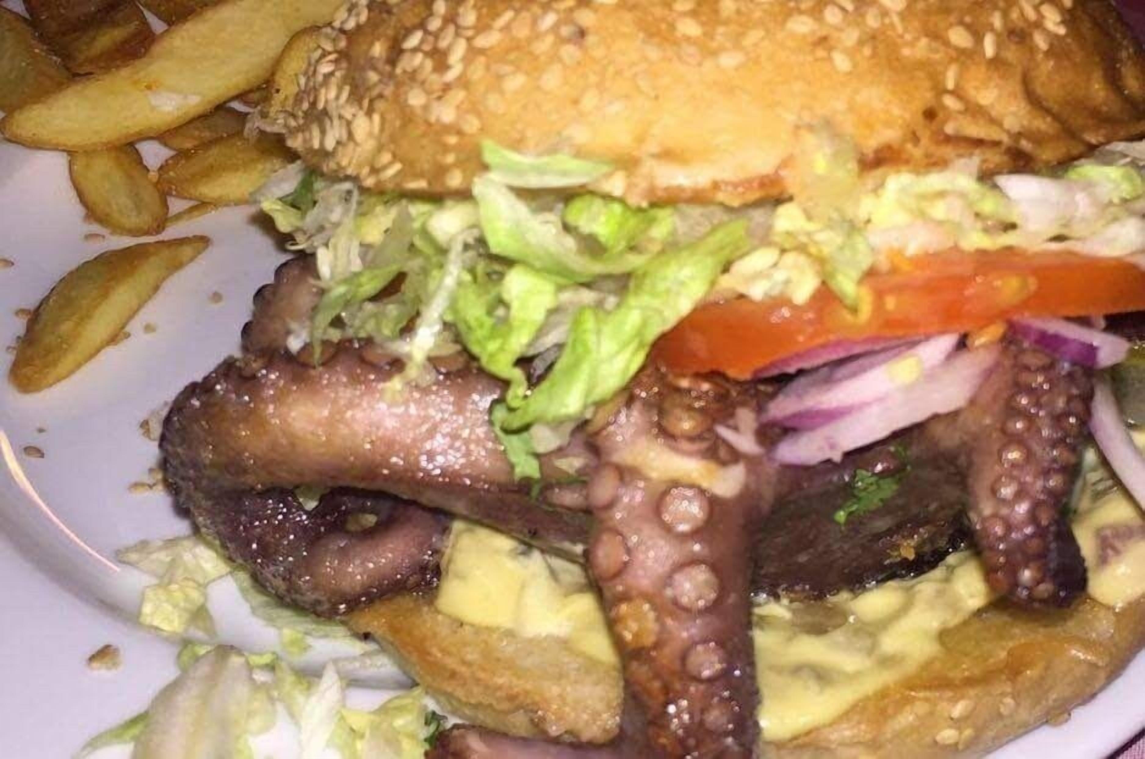 A burger with lettuce, tomato, and onion, served with fries.