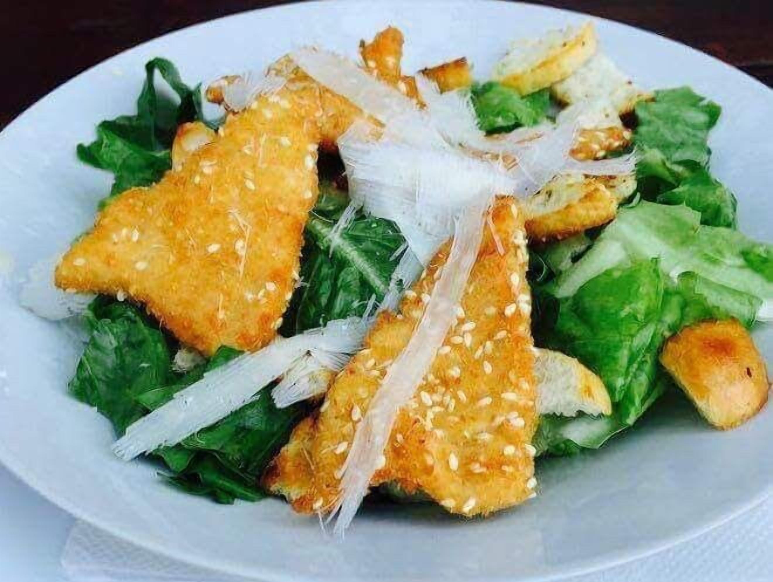 A plate of food with a salad and bread pieces.