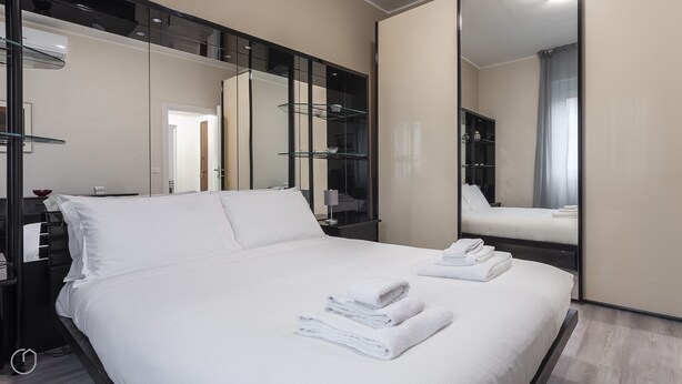 Una habitación de hotel con una cama grande, un espejo y un armario.