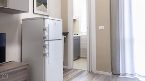 Una cocina compacta con un refrigerador blanco, un mueble pequeño y otro de madera.