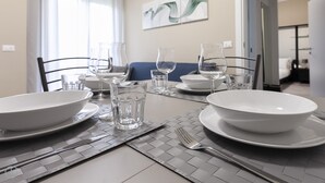 Una mesa de comedor dispuesta con cuencos blancos, vasos y cubiertos.