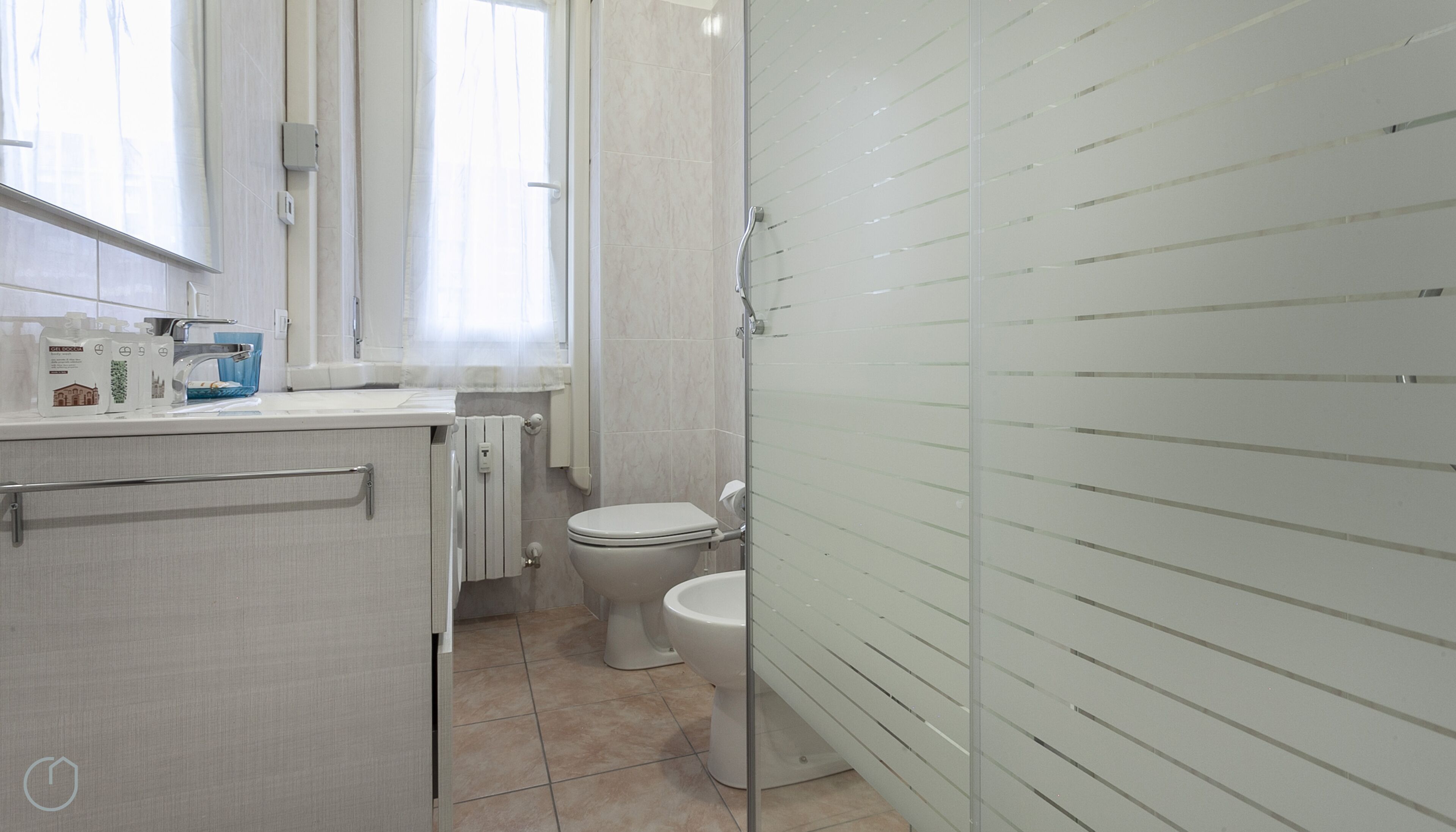 A bathroom with a toilet, a shower, and a sink.