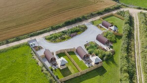 Vista aérea de una granja con graneros, un camino pavimentado y campos circundantes.