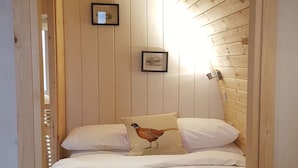 Una habitación acogedora con cama, paredes de madera y techo inclinado.