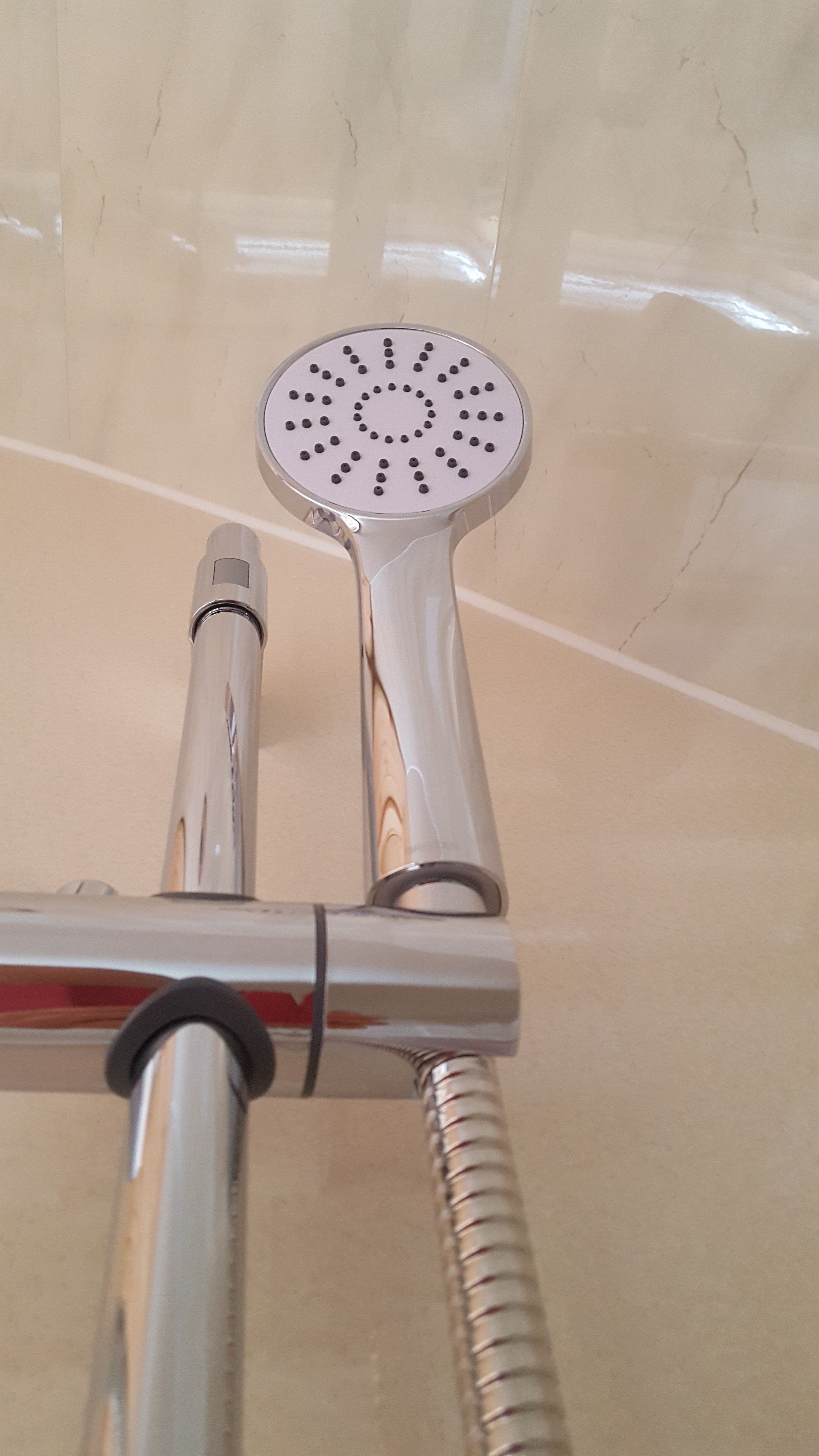 Un pommeau de douche au design circulaire et doté d’un panneau de commande.