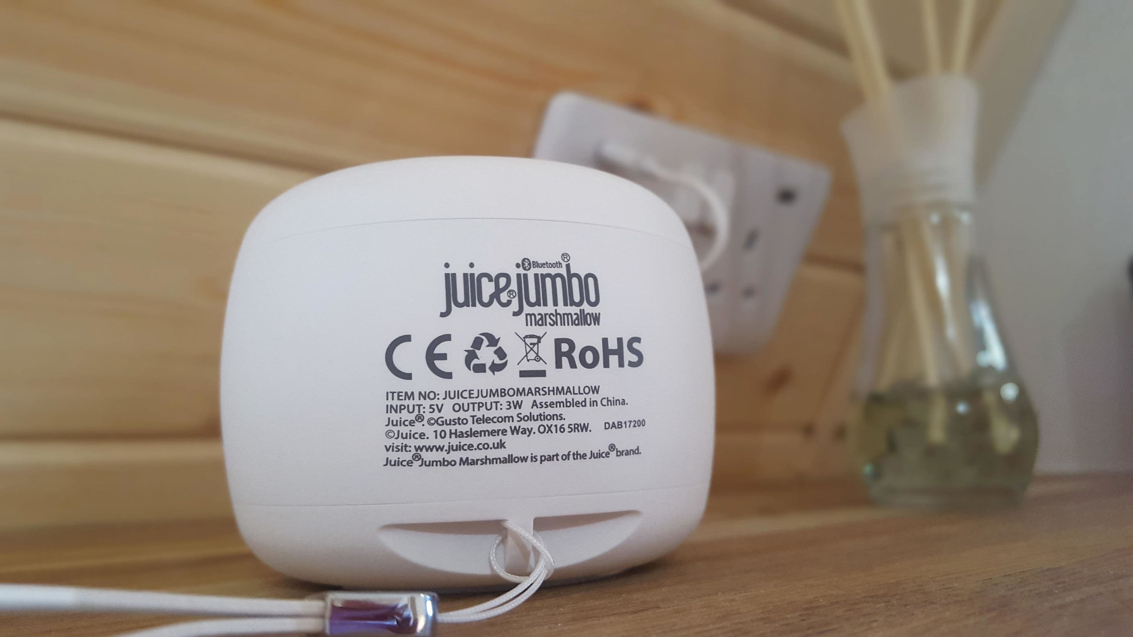 A white electronic device with text and symbols indicating it is a Juice Jumbo Marshmallow, a Bluetooth-enabled product with CE and RoHS certifications.