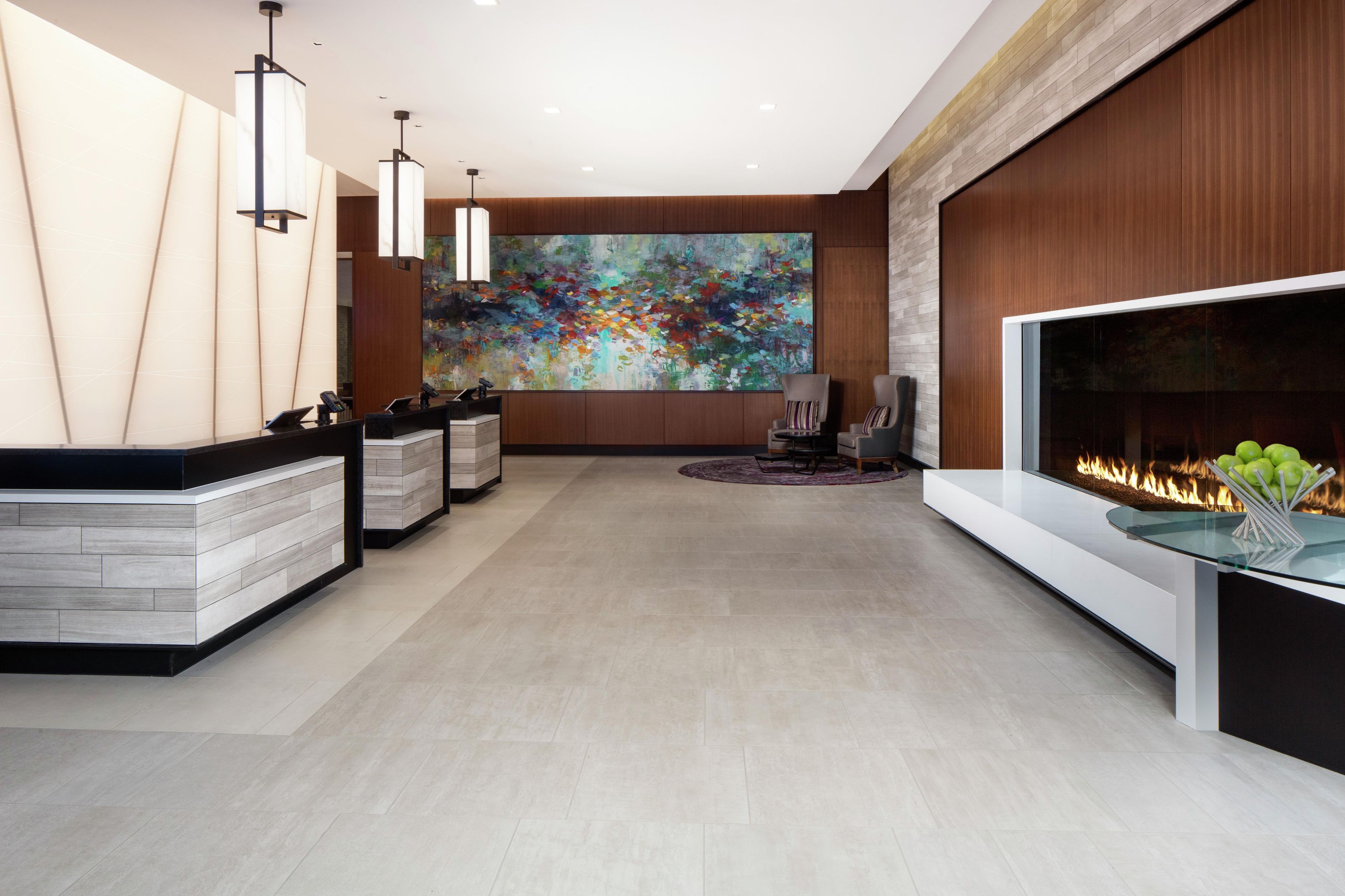 A modern reception area with a large abstract painting, a reception desk, and a fireplace with a fire.
