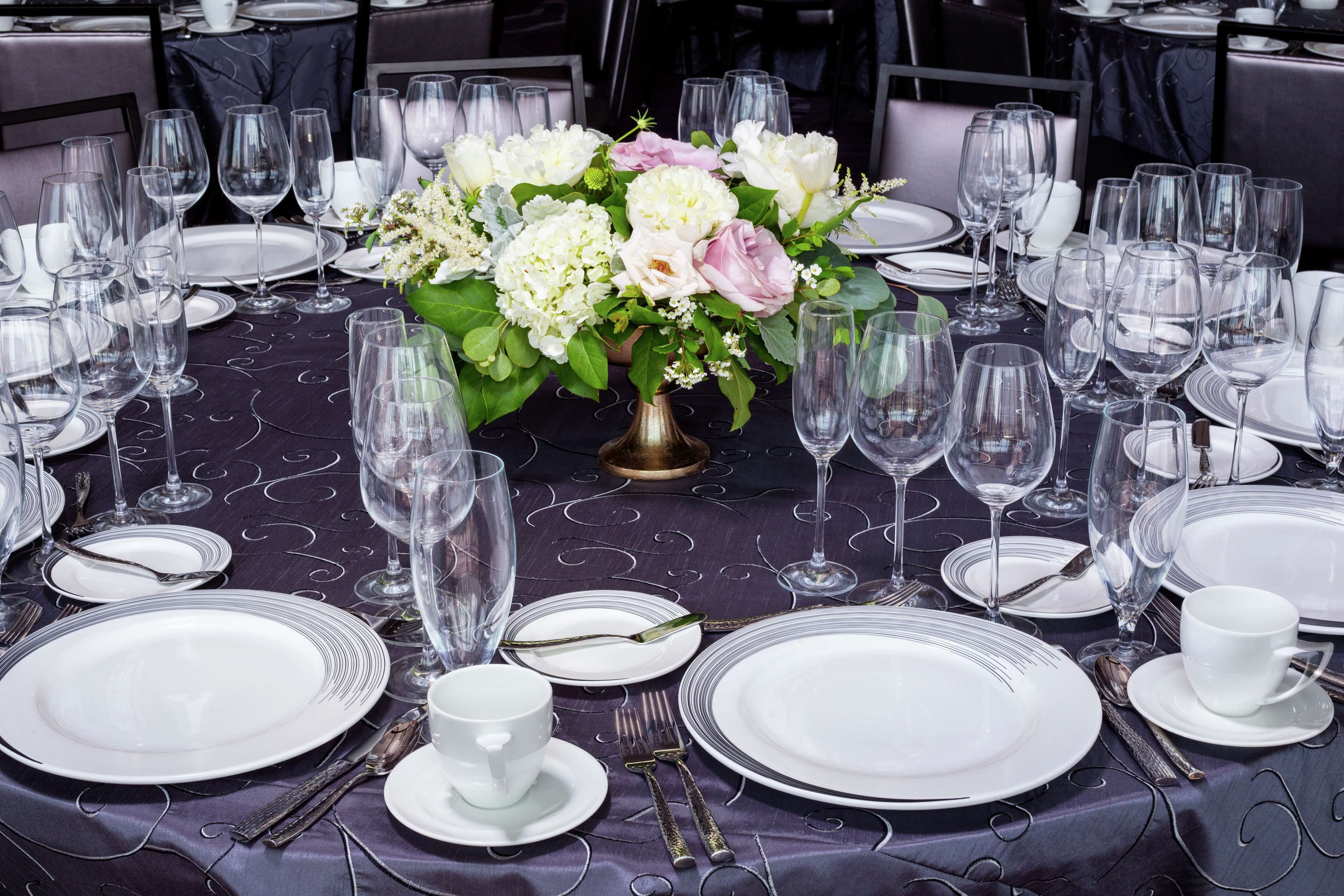 A table set for a formal dinner with multiple wine glasses, plates, and cutlery.