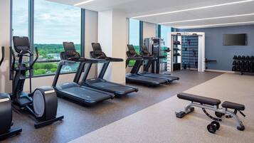 Un gimnasio con cintas de correr, elípticas y equipo de levantamiento de pesas.