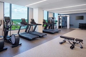 Une salle de sport équipée de tapis de course, de vélos elliptiques et de matériel de musculation.
