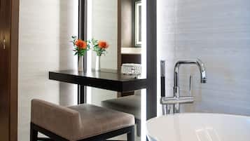 A modern bathroom with a large mirror, a bathtub, and a bench.