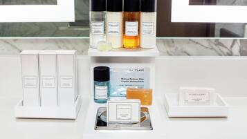 Un meuble-lavabo de salle de bain contenant des articles de toilette, notamment du shampoing, de l’après-shampoing, du gel douche, une lotion pour le corps, un bain de bouche, une lingette démaquillante, un savon pour le visage et un savon pour les soins de la peau.