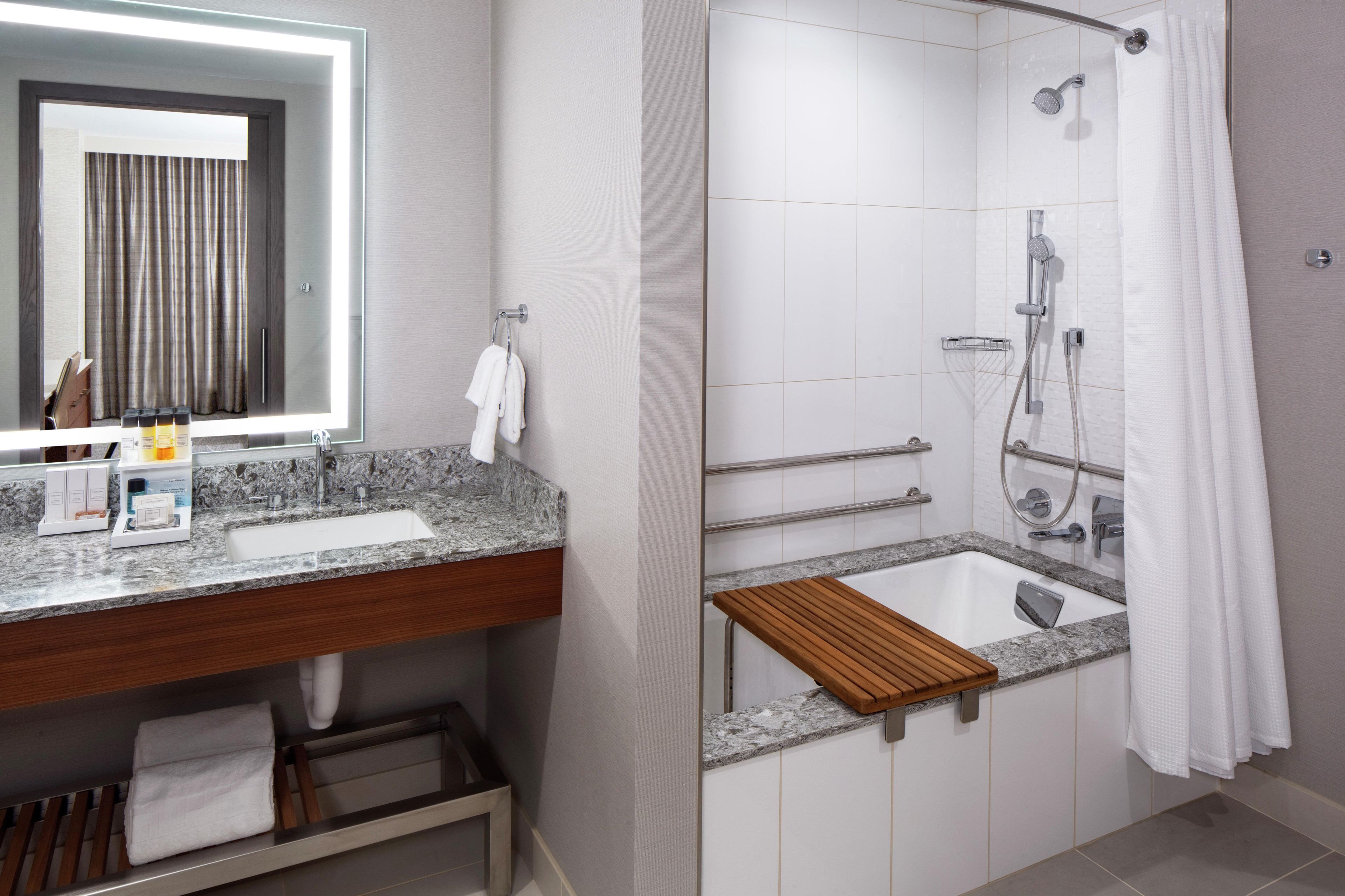 Un baño moderno con tocador, lavabo, espejo y zona de ducha.