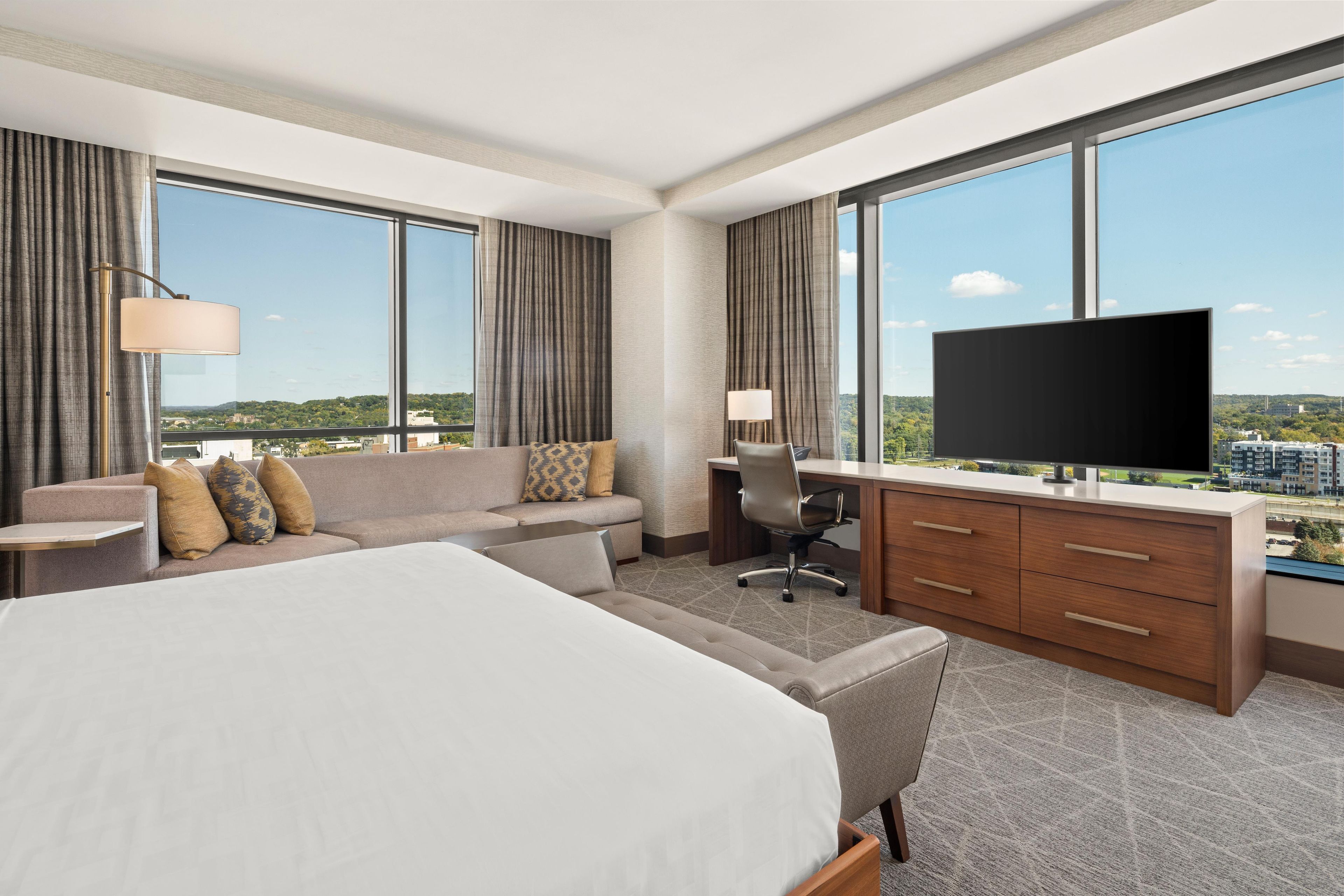 Habitación de hotel con una cama grande, un sofá, un escritorio y un televisor.