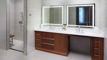 A modern bathroom with a glass shower enclosure, a double sink vanity with wooden cabinets, and a large mirror above the vanity.