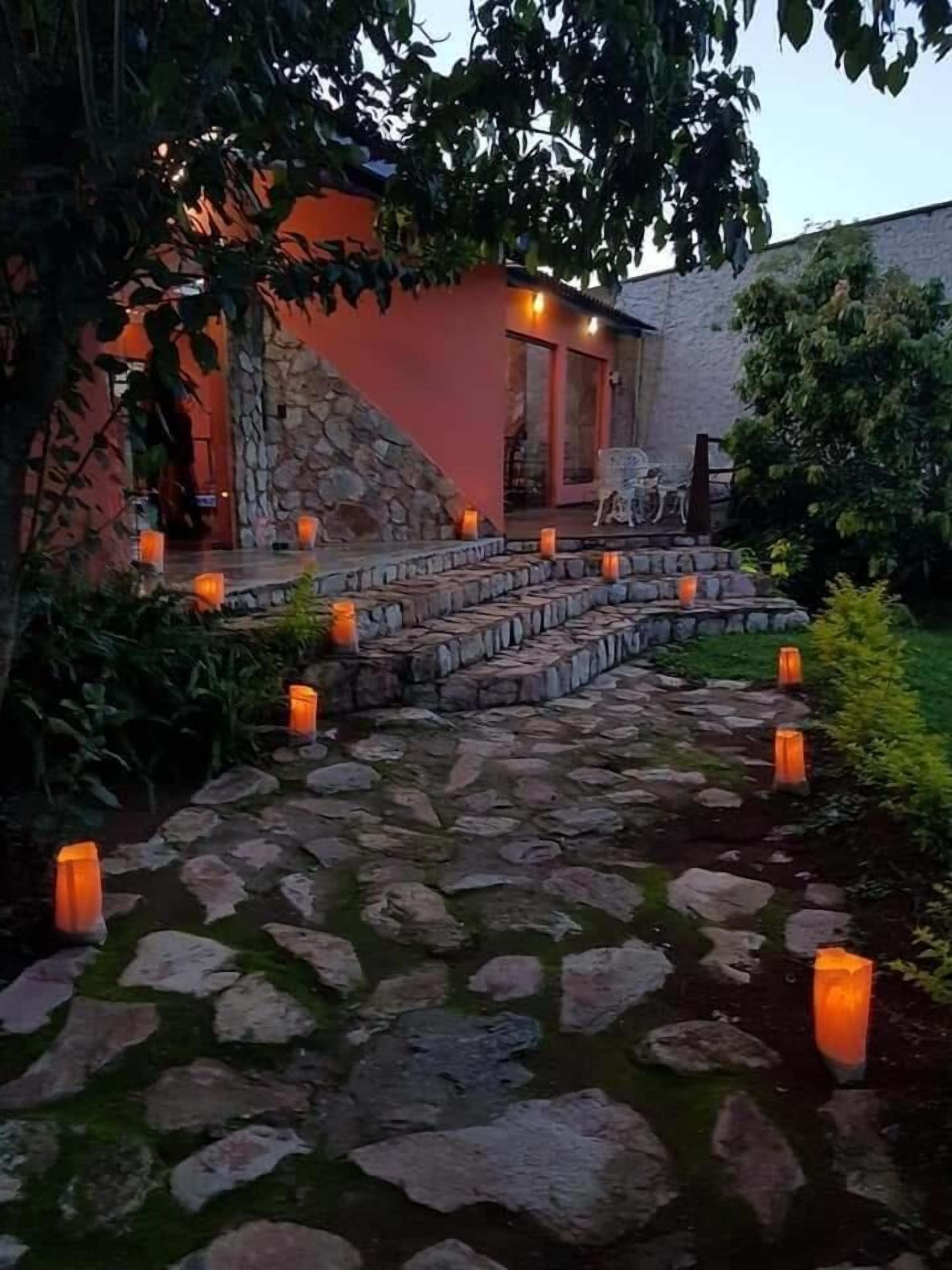 A stone pathway leading to a building with a stone wall and a door.