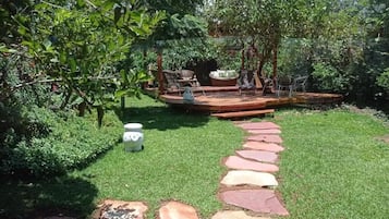 A garden with a stone pathway leading to a seating area with chairs and a table.