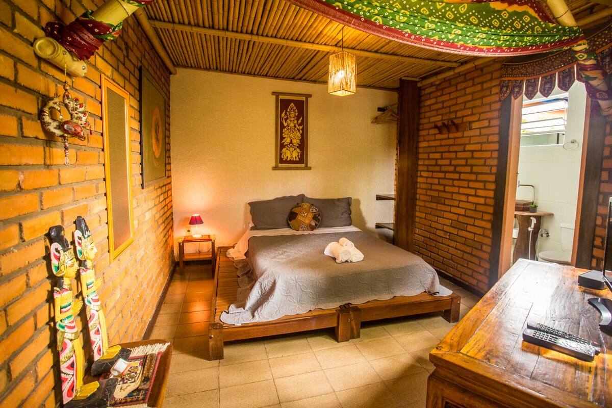 Una habitación con una cama, un escritorio de madera y un adorno colgante en la pared.
