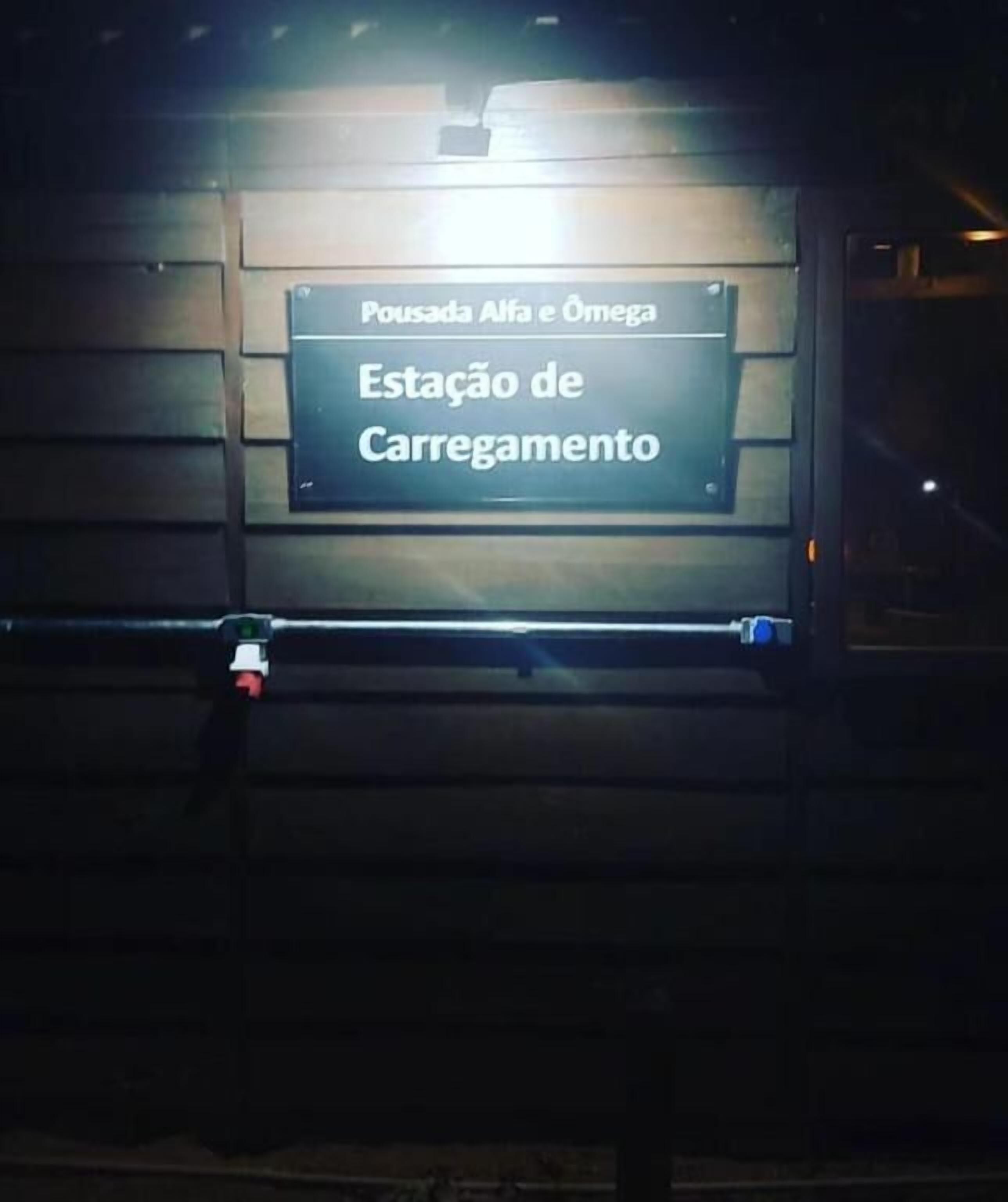 A sign with the text "Pousada Alfa e Omega" and "Estação de Carregamento" indicating a loading station.