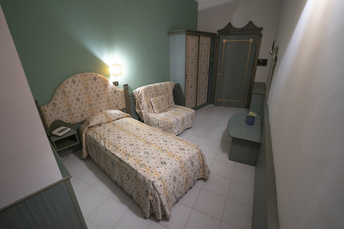 Ein Schlafzimmer mit zwei Einzelbetten, einem Nachttisch, einem Kleiderschrank und einem kleinen Tisch mit einer Pflanze.