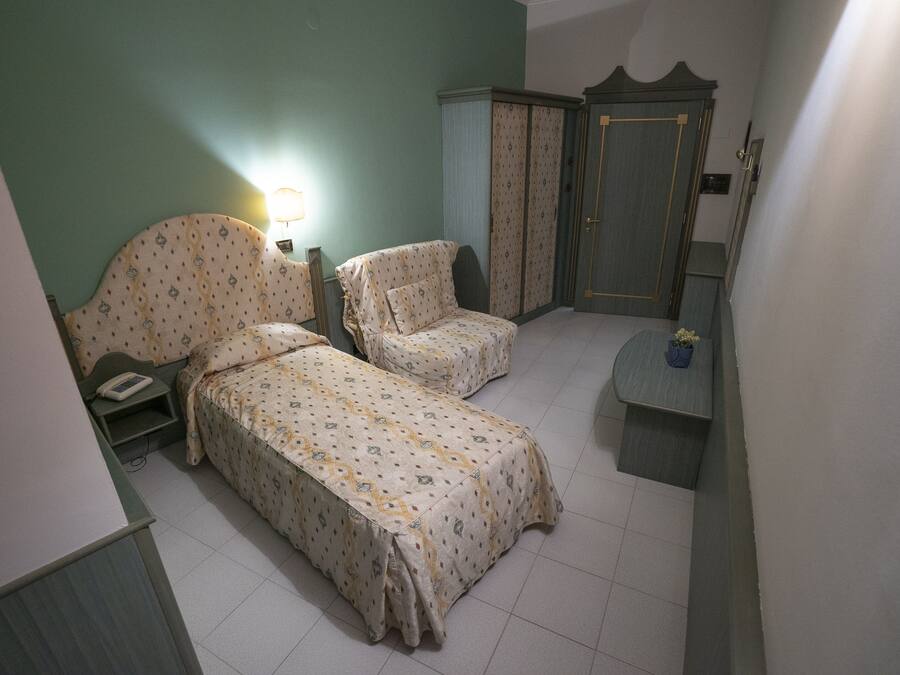 Ein Schlafzimmer mit zwei Einzelbetten, einem Nachttisch, einem Kleiderschrank und einem kleinen Tisch mit einer Pflanze.