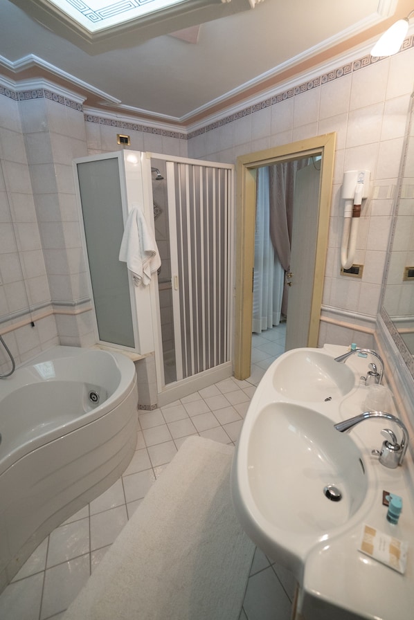 A bathroom with a bathtub, two sinks, a shower, and a mirror.